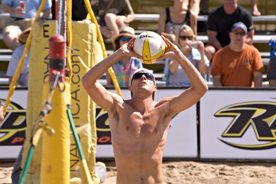 Beach setting - A male volleyball plater hand setting a ball in a beach game